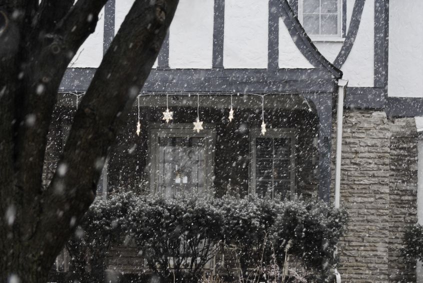 a snowy day in front of a house that has been decorated for the season.